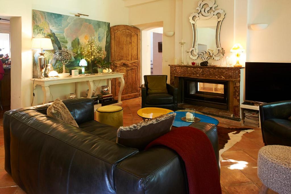 a living room with a leather couch and a fireplace at La Grande Maison De Nans in Nans-les-Pins