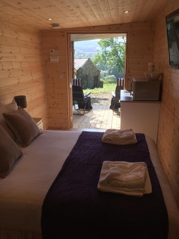 een groot bed in een kamer met een groot raam bij Romantic Getaway Luxury Wooden Cabin With Private Hot Tub and BBQ in Aberystwyth