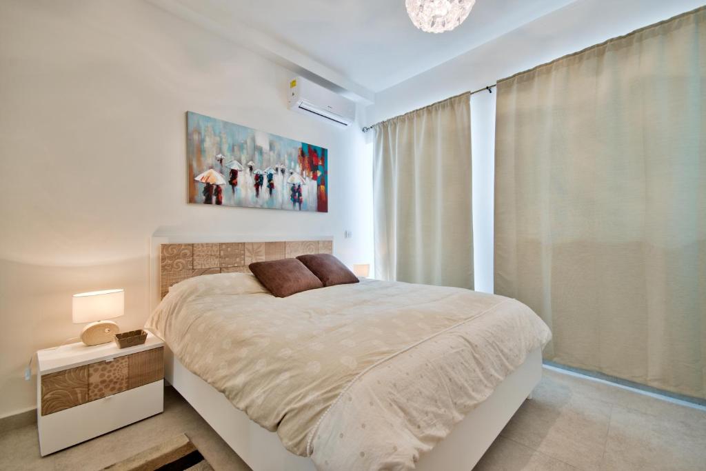 a white bedroom with a bed and a window at "Centre Point" Apartment in St. Julianʼs