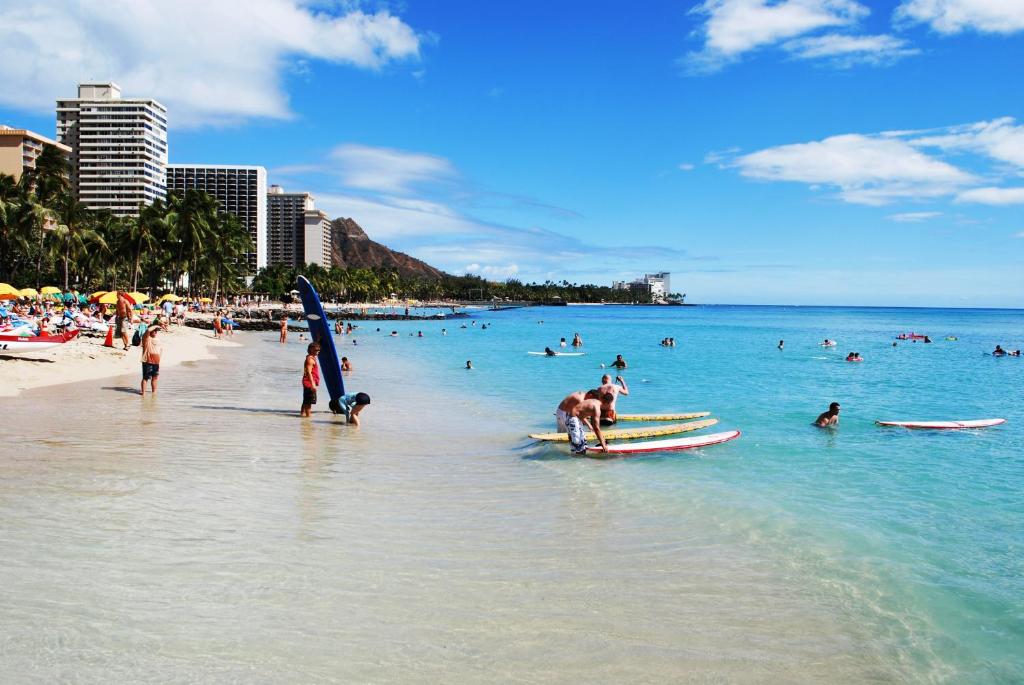 eine Gruppe von Menschen am Strand im Wasser in der Unterkunft Waikiki Sunset Apartment in Honolulu