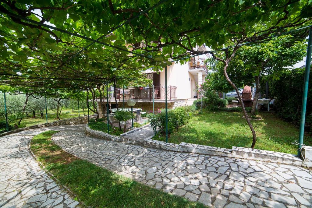 un jardín con un camino de piedra frente a una casa en Apartments Marija, en Poreč