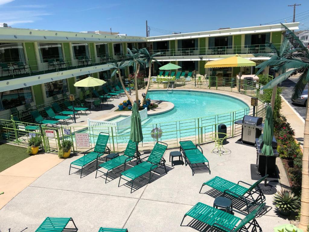 una piscina con sillas verdes y sombrillas en un hotel en Caribbean Motel, en Wildwood Crest