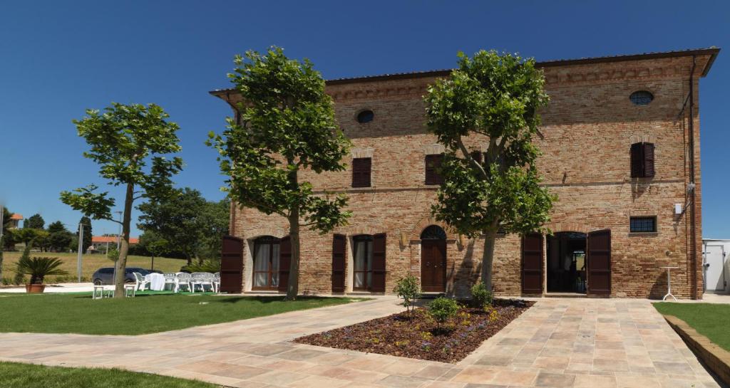 un edificio in mattoni con alberi di fronte di villa Resort Tre Castelli a Ripe
