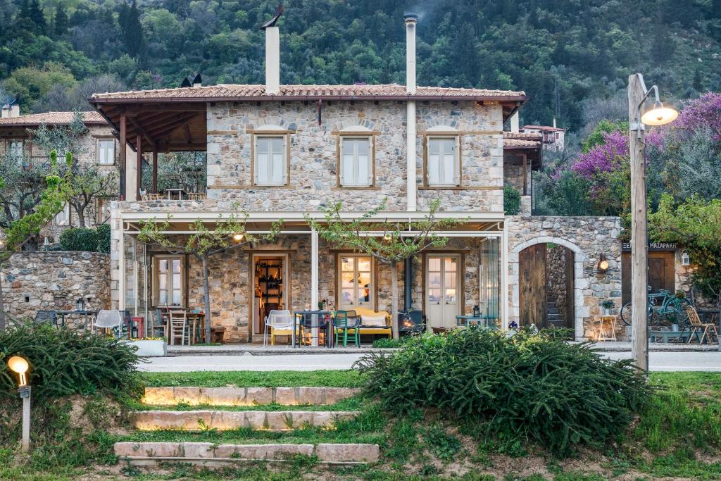 una casa in pietra con un tavolo e sedie di fronte di Mazaraki Guesthouse a Mystras (Mistra)