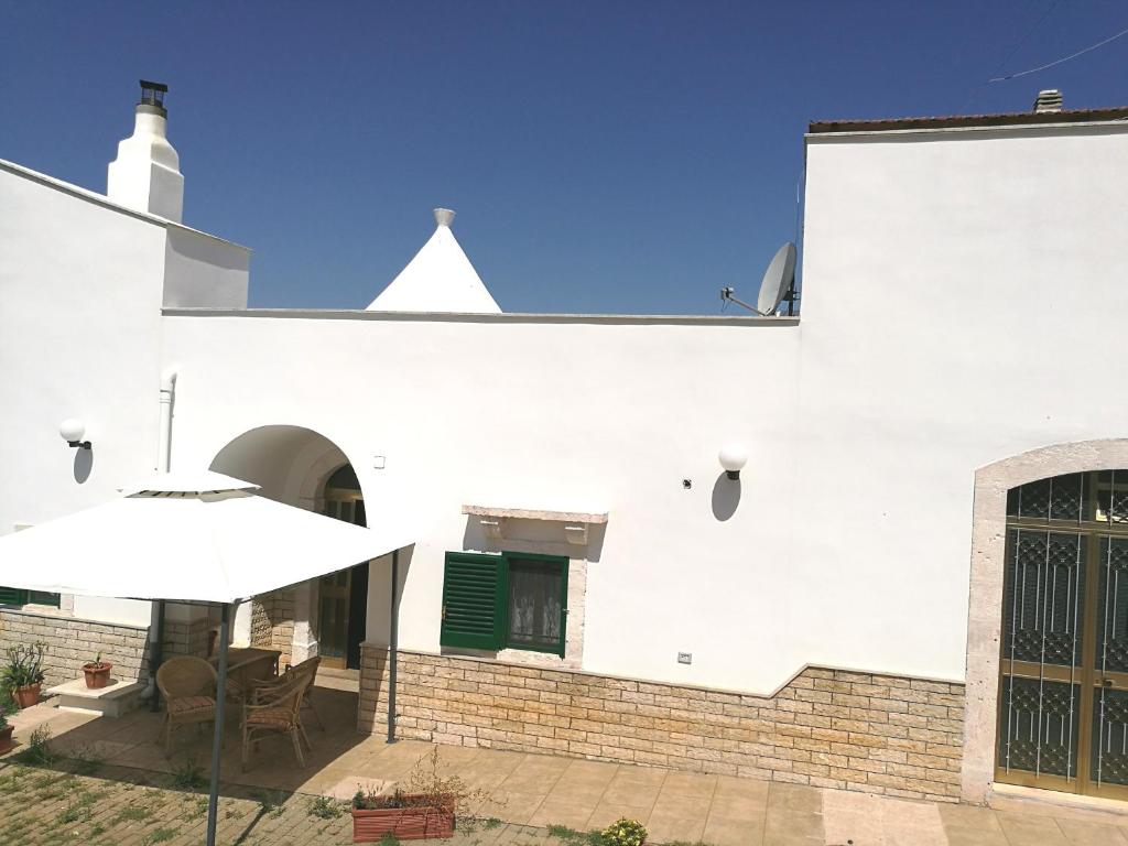 ein weißes Gebäude mit einem Tisch und einem Regenschirm in der Unterkunft Il Trullo di Nonna Enza in Castellana Grotte