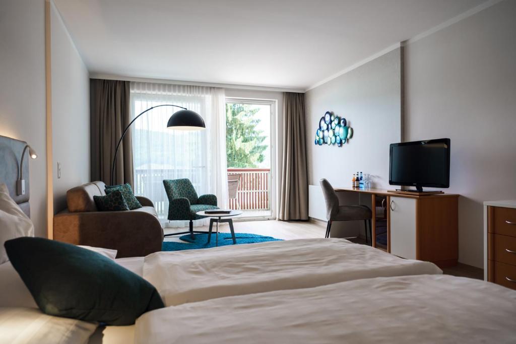 um quarto de hotel com duas camas e uma televisão em Seehotel Vinzenz em Velden am Wörthersee