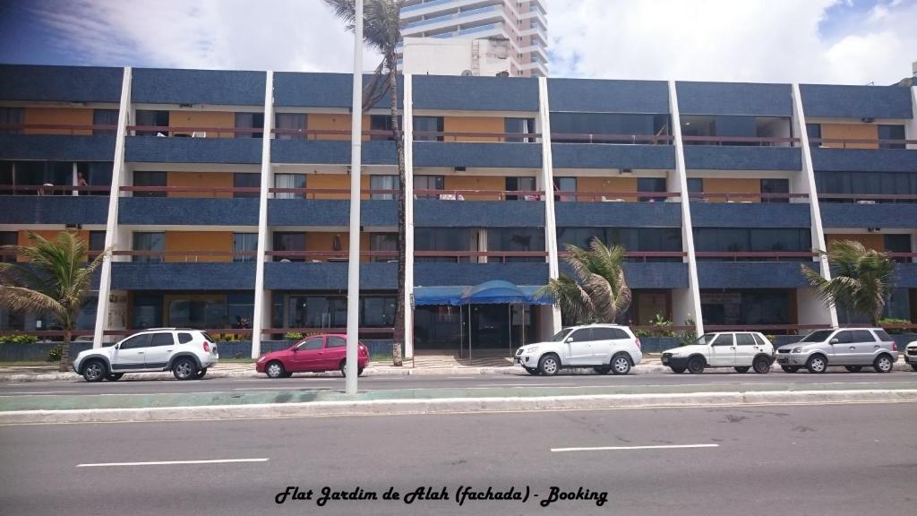 a large building with cars parked in front of it at Flat Jardim de Alah in Salvador