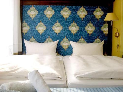 two beds with white pillows in a bedroom with a blue wall at Hotel Neustadt in Osnabrück