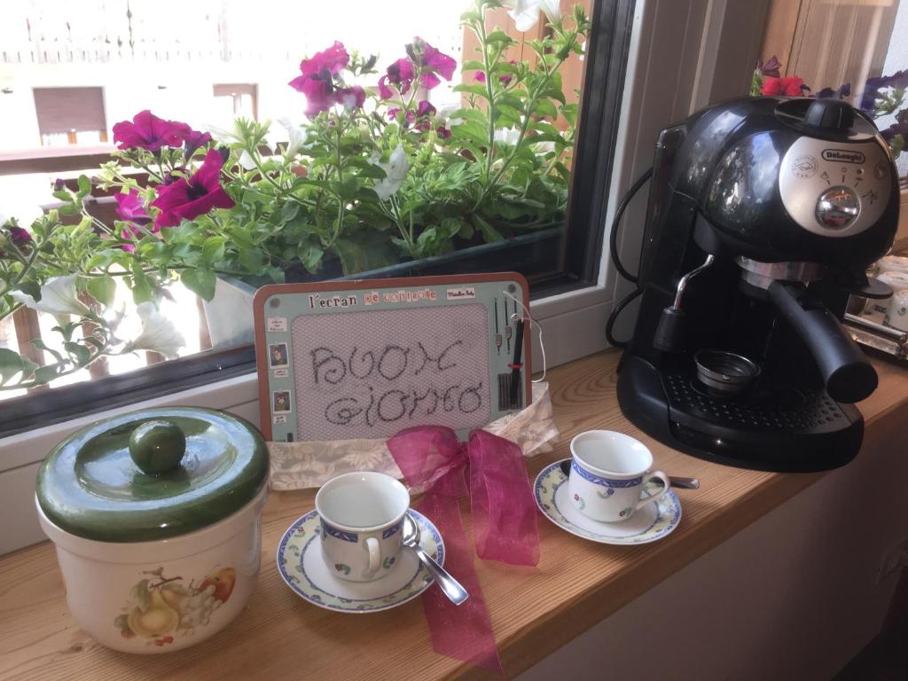 una mesa con dos tazas, una cafetera y un cartel en b&b Casa Tavernaro en Fiera di Primiero