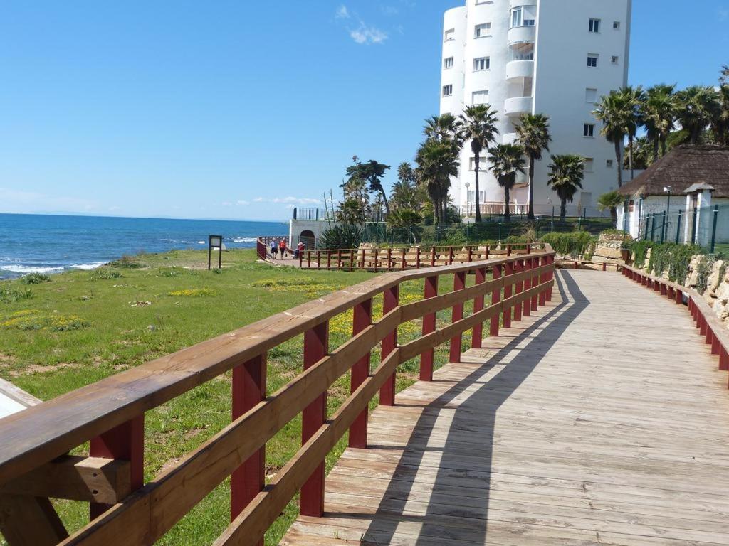 a wooden boardwalk next to a beach with a building at Apartamento Club Algaida Beach in Mijas Costa
