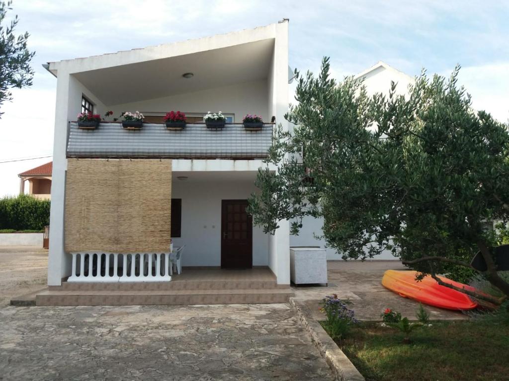 a white house with a balcony with flowers on it at Apartments Stipanovic in Biograd na Moru