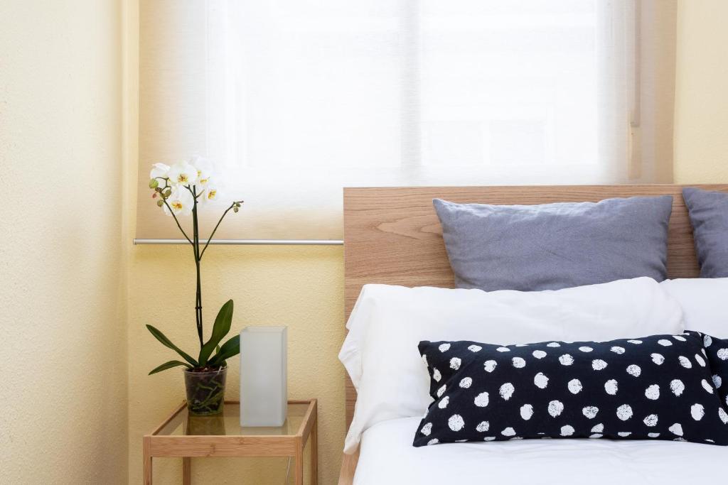 una camera da letto con un letto e un vaso di fiori su un tavolo di Calidez en Malasaña - Nix a Madrid