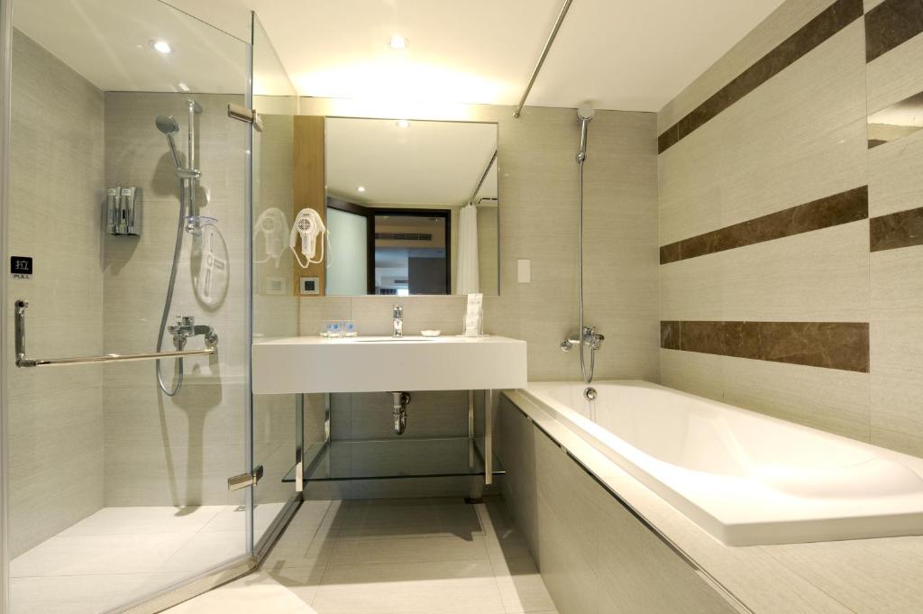 a bathroom with a sink and a tub and a mirror at International Citizen Hotel in Kaohsiung