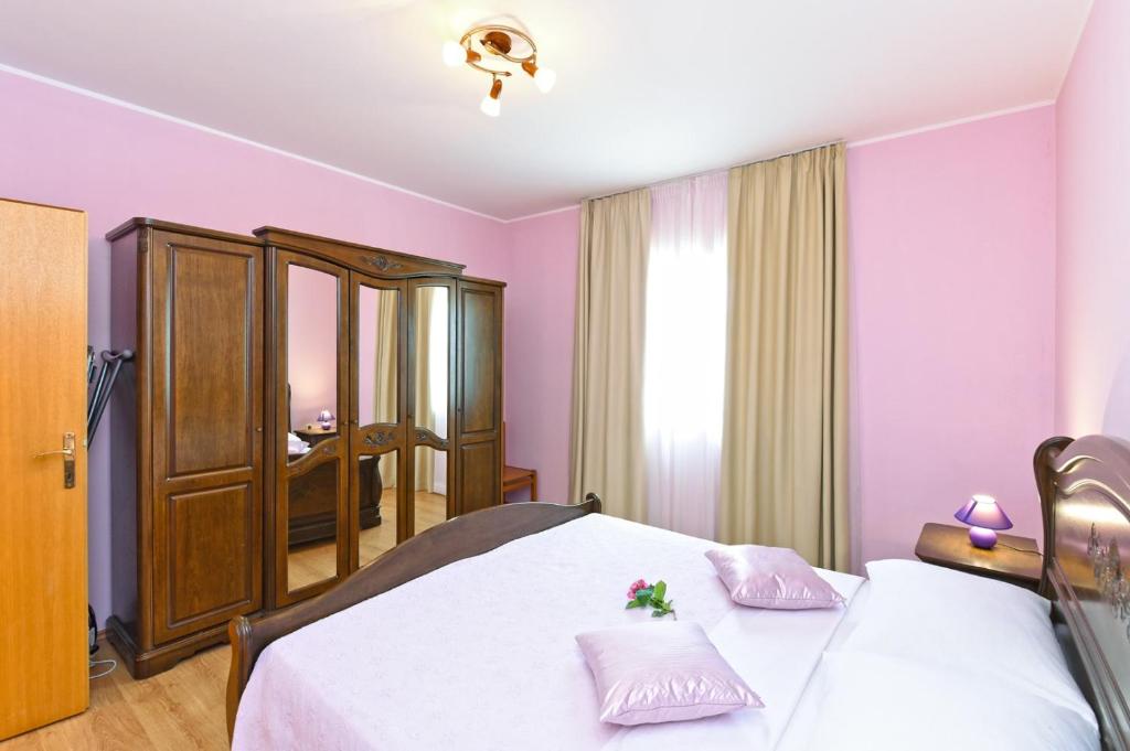 sypialnia z 2 łóżkami i różowymi ścianami w obiekcie Apartment Dvori with pool w mieście Kaštelir