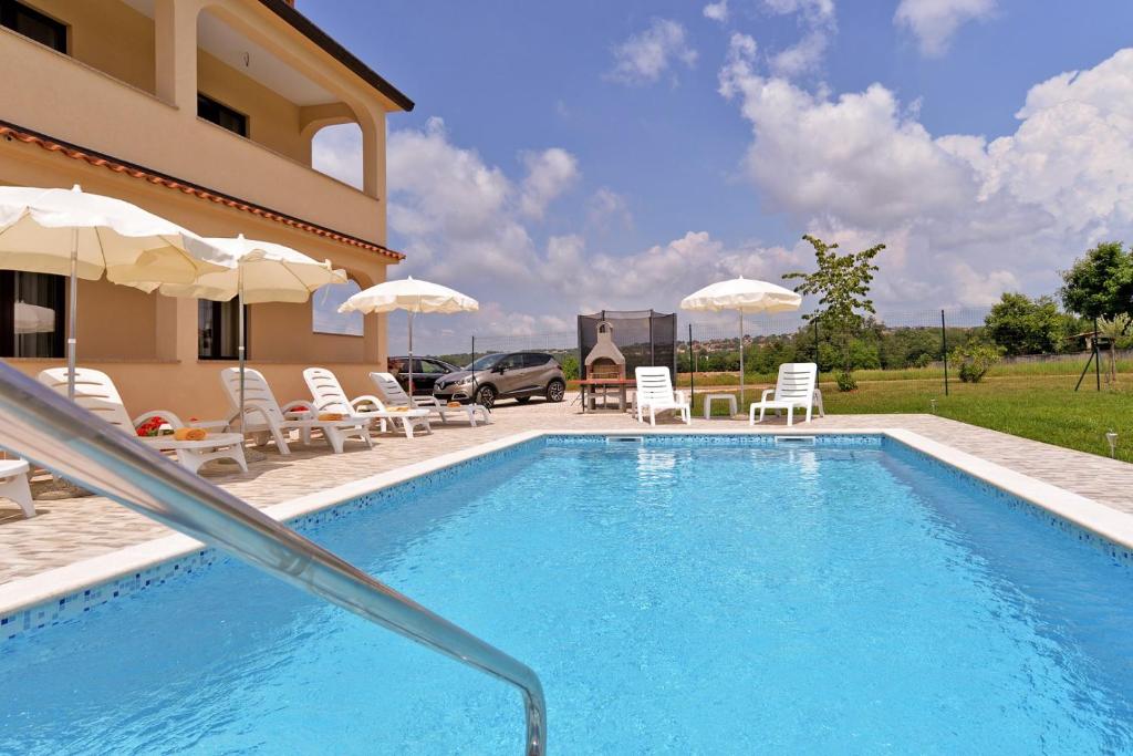 basen z leżakami i parasolami obok domu w obiekcie Apartment Dvori with pool w mieście Kaštelir