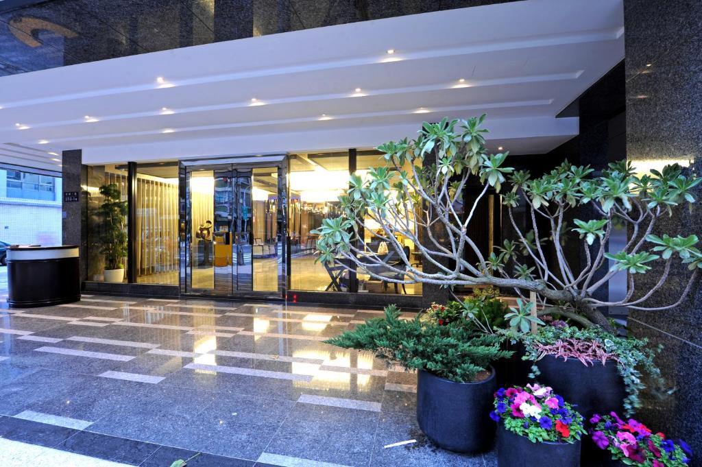 a lobby with potted plants in front of a building at International Citizen Hotel in Kaohsiung