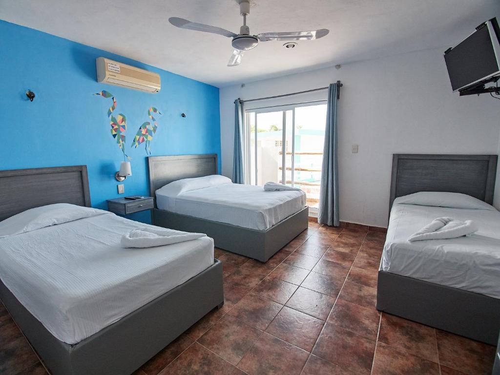 2 camas en una habitación con paredes azules en Hotel Tabasco Rio, en Río Lagartos