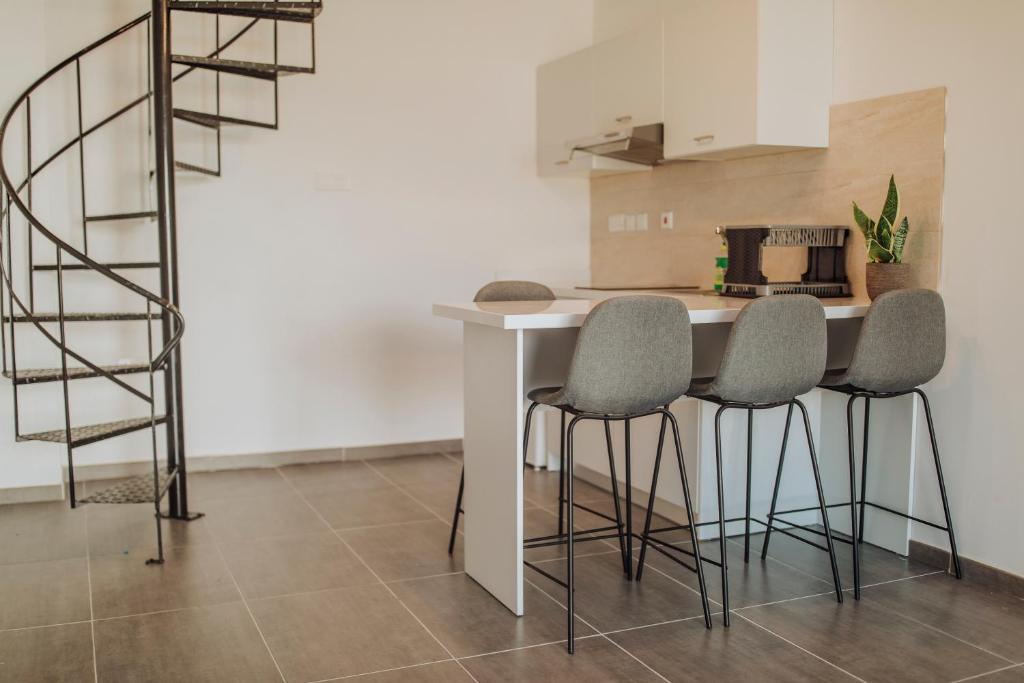 a kitchen with a table with four chairs and a spiral staircase at River View Boutique Apts in Ayia Napa