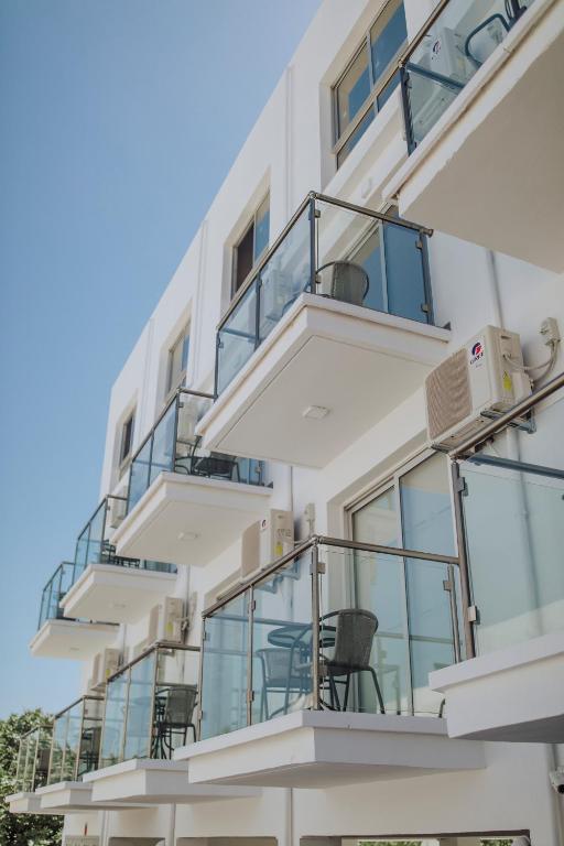 a white building with balconies and chairs on it at River View Boutique Apts in Ayia Napa