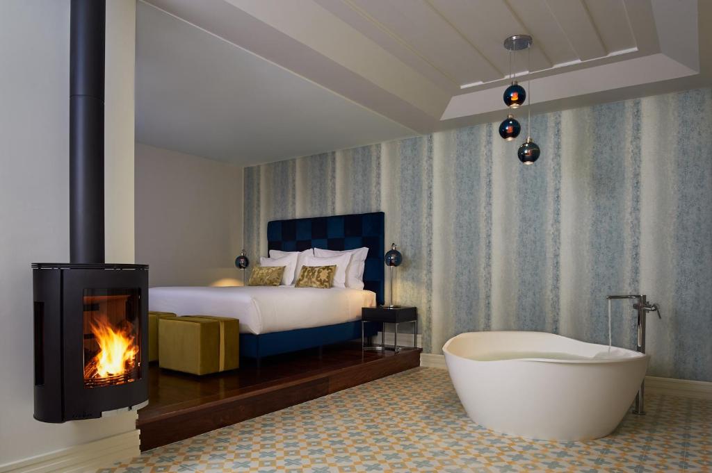 um quarto com uma banheira, uma cama e uma lareira em Convento do Seixo Boutique Hotel & Spa no Fundo
