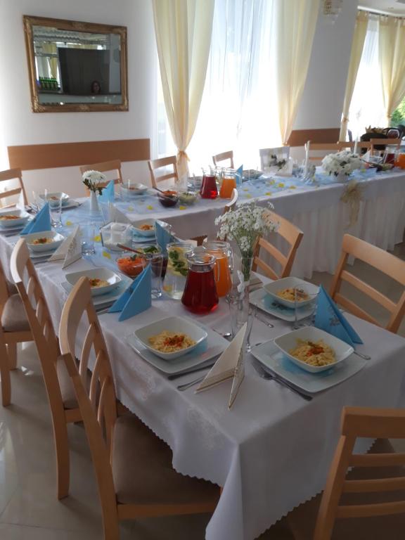 Biesiadny Dworek في Szpegawa: طاولة بيضاء طويلة مع أطباق من الطعام عليها