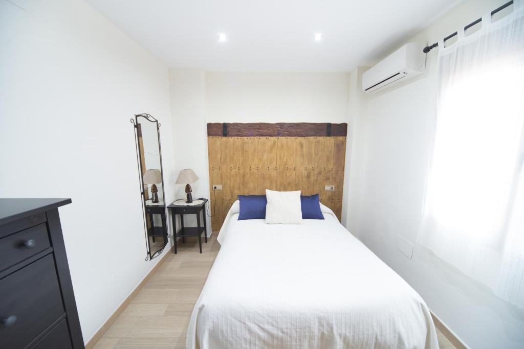 Un dormitorio con una cama blanca y un cabecero de madera. en Los Toneles, en Puerto de Santa Cruz