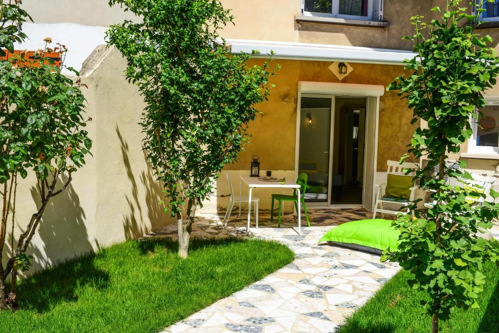 un jardin avec une terrasse, une table et des arbres dans l'établissement Studio les Hortensias, à Avignon