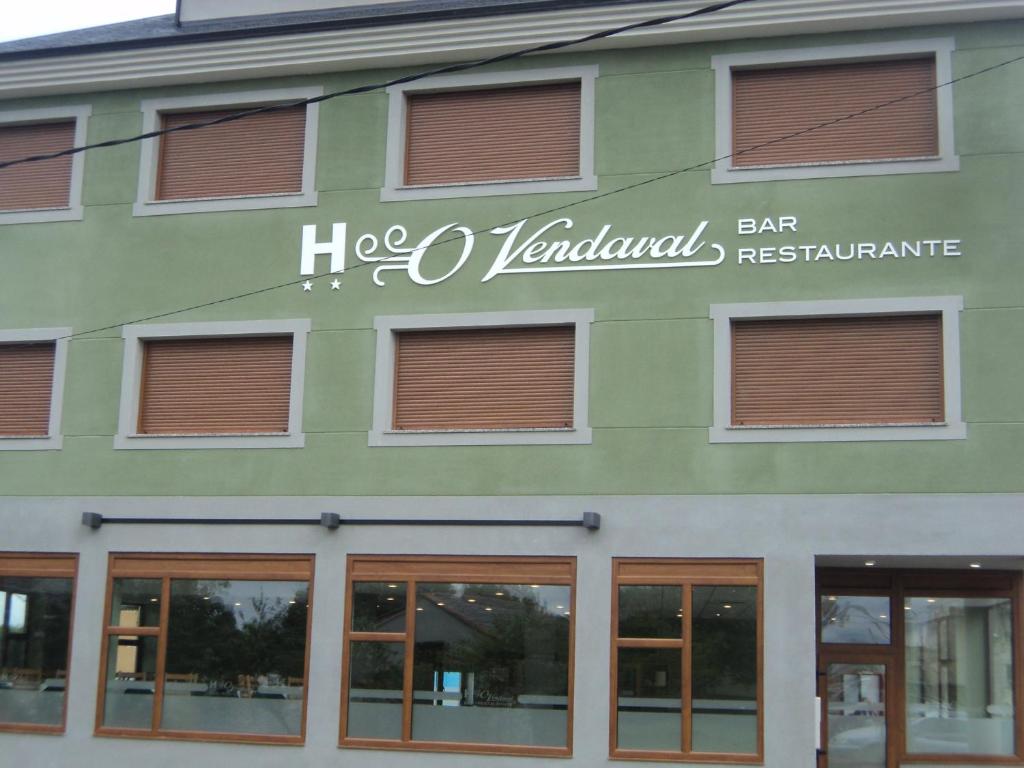 un edificio verde con un cartel en el costado en O Vendaval Hostal Restaurante, en Barreiros