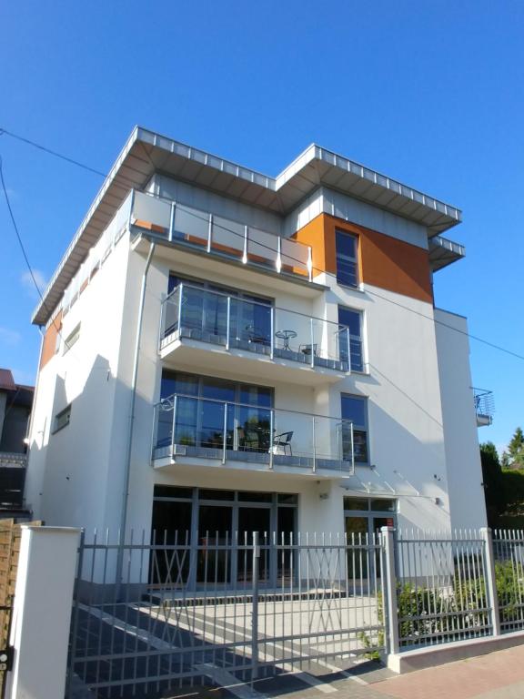 a white building with a fence in front of it at Aparthotel Luna&Sol in Jastrzębia Góra