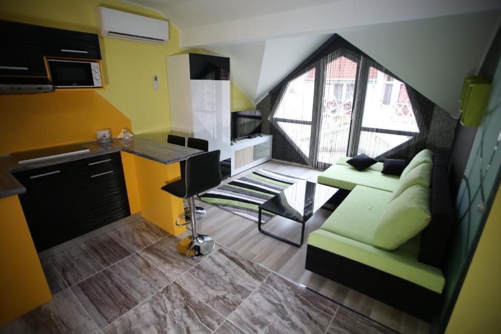a living room with a green couch and a kitchen at Centrum Lux 2 Apartmanok in Kaposvár
