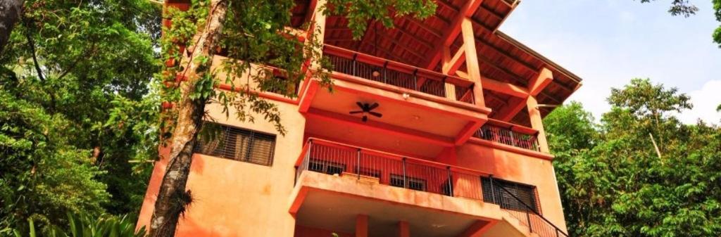 a tall red building with trees in front of it at Hotel Rio in La Ceiba