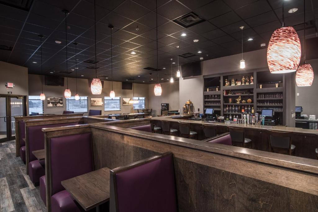 a restaurant with a bar with purple chairs at Astoria Extended Stay & Event Center in Dickinson