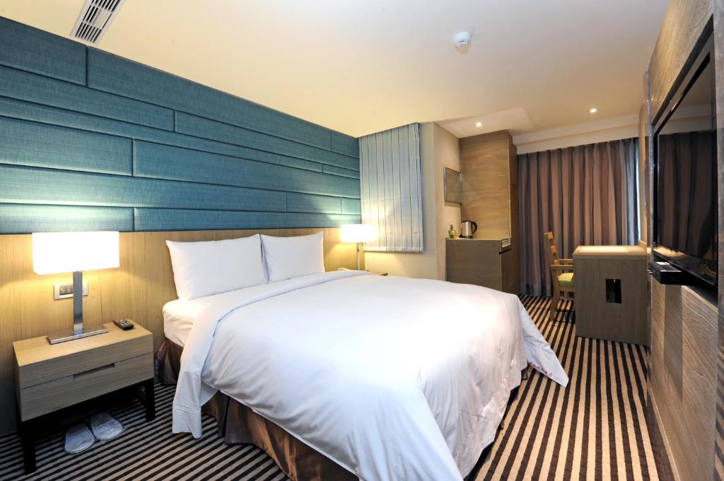 a bedroom with a large white bed and a blue wall at International Citizen Hotel in Kaohsiung