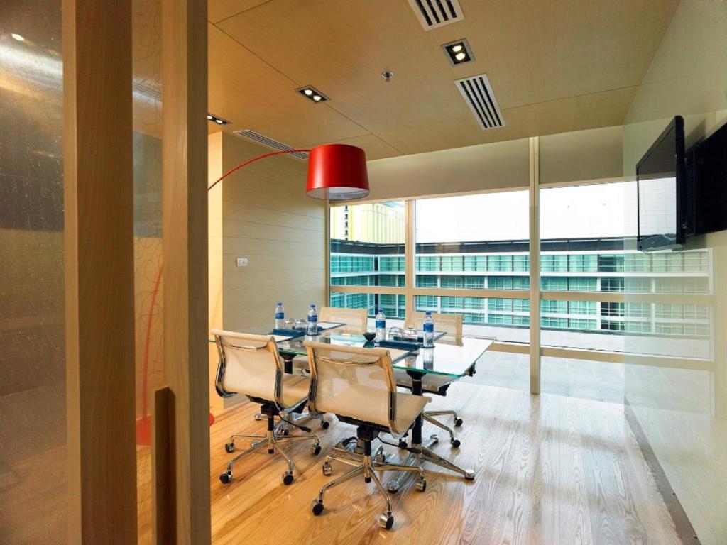 A compact glass-walled meeting room with a four-seat table and city-facing windows.