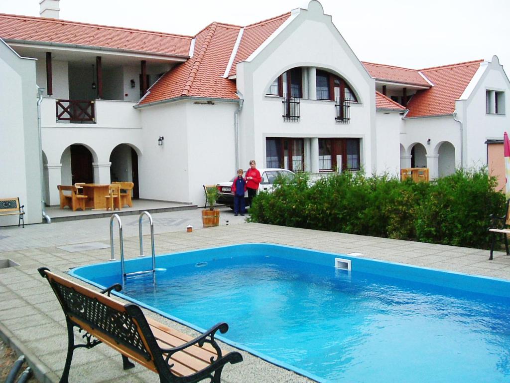 a swimming pool with a bench in front of a house at Szanyi Vendégház in Hegykő
