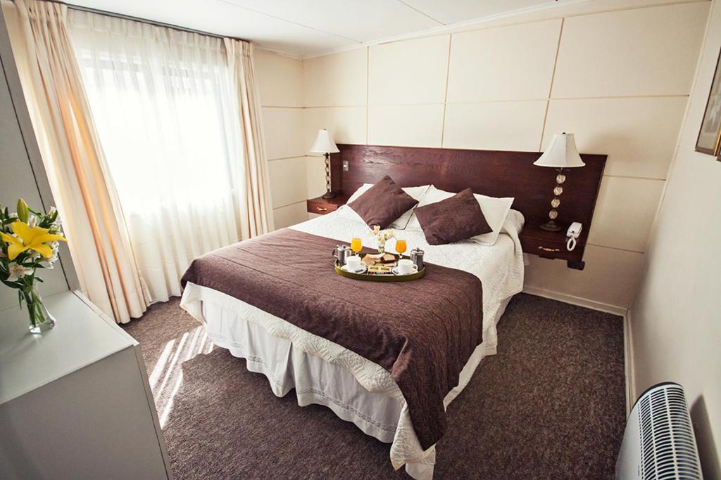 Una habitación de hotel con una cama con una bandeja de comida. en Hotel Albamar, en Viña del Mar