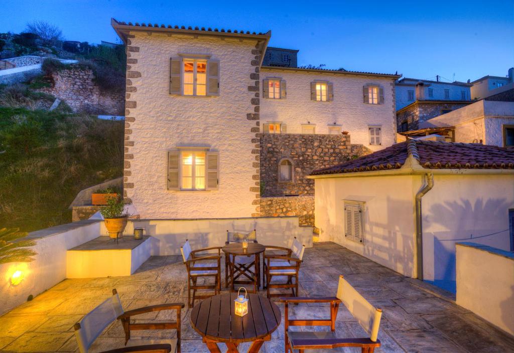 um pátio com mesas e cadeiras em frente a um edifício em Nereids Guesthouse em Hydra