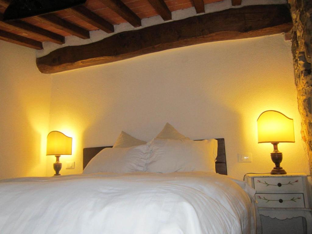 a bedroom with a white bed with two lamps at Castello di Civitella in Civitella in Val di Chiana