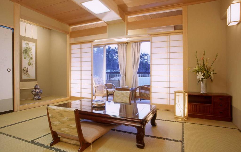 a living room with a table and chairs and a window at Hotel Spax Kusatsu in Kusatsu