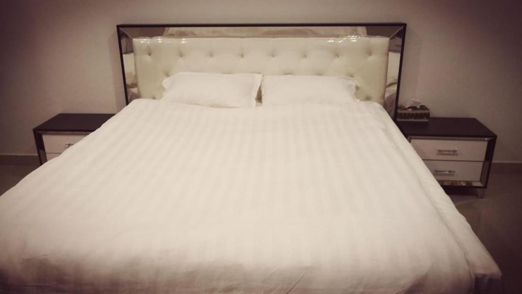 a bed with white sheets and pillows on it at Almalki furnished units in Al Thybiyah