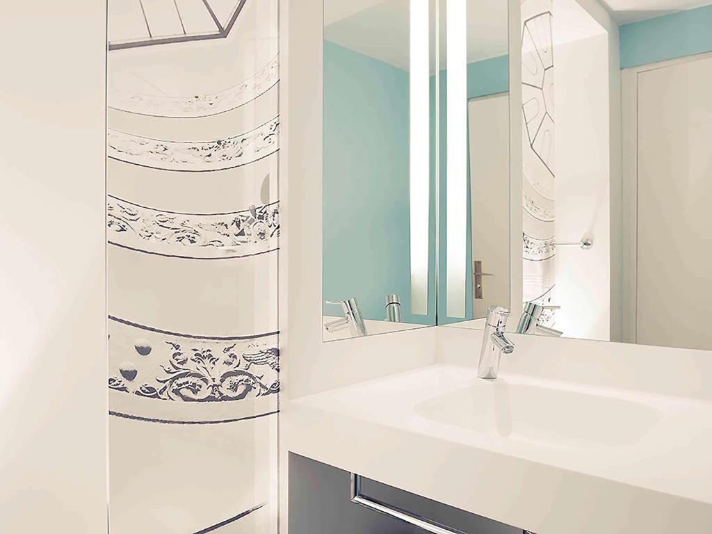 a white bathroom with a sink and a mirror at Mercure Lyon Centre Beaux-Arts in Lyon