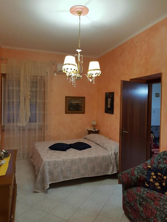 een slaapkamer met een bed en een kroonluchter bij Bed and breakfast Marilena in Montegiordano
