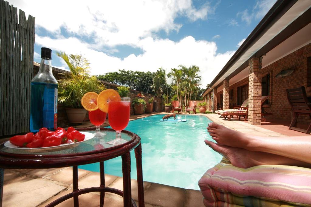 a person sitting on a chair next to a swimming pool with drinks at Marlin Lodge St Lucia in St Lucia