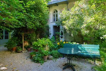 un banc vert devant une maison avec des plantes dans l'établissement Bel Appartement Dans Cloitre Arbore, à Villeneuve-lès-Avignon