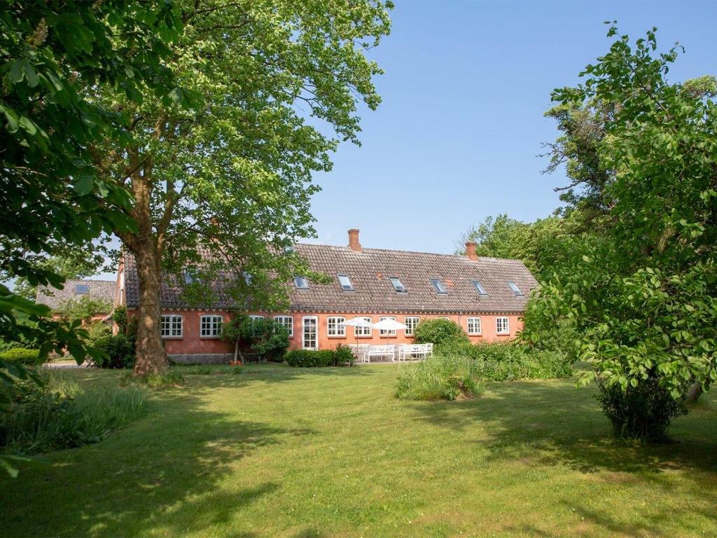 a large red brick house with a large yard at Mellem-rummet Guesthouse & Glamping in Tanderup