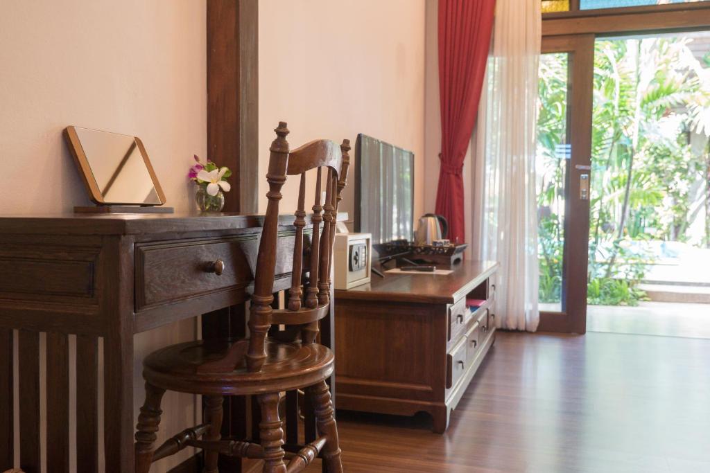 A traditional writing desk beside a television cabinet and garden-facing glass door.