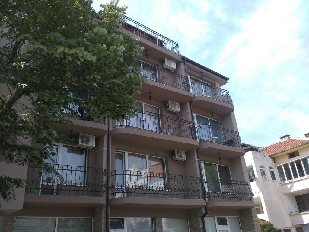 ein Apartmenthaus mit Balkon und einem Baum in der Unterkunft Guest House Stenli in Primorsko