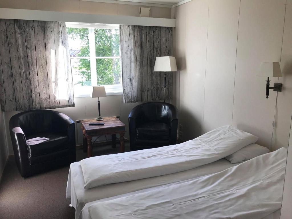 a hotel room with a bed and two chairs and a table at Rørosvidda Hotell in Røros