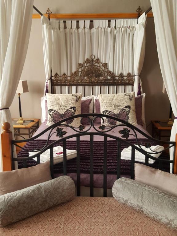 um quarto com uma cama de ferro forjado e almofadas em Cecil John Rhodes Guest House em Kimberley