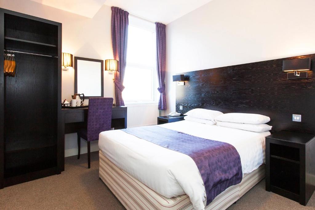 a hotel room with two beds and a television at The Abbey Lodge Hotel in Bradford